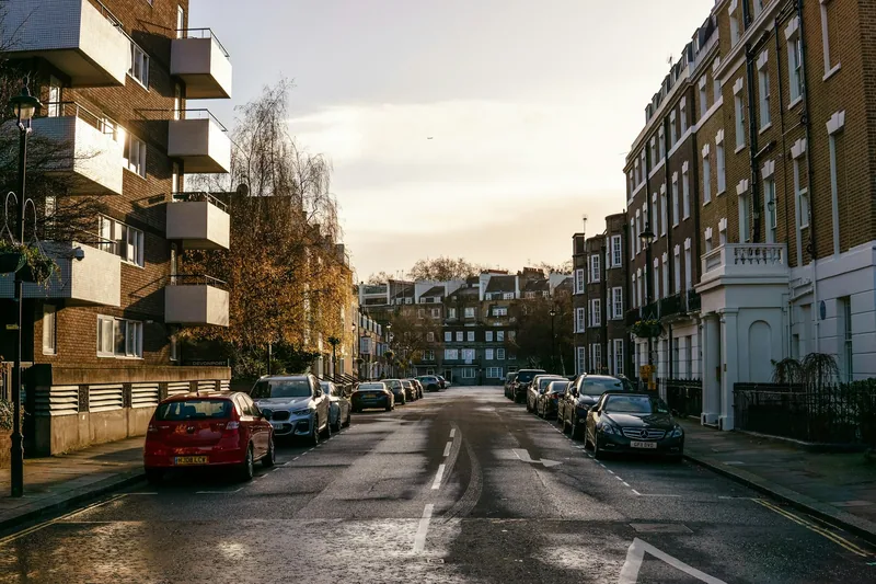 Stille boliggate i London med biler parkert langs begge fortauskantene i ettermiddagssol