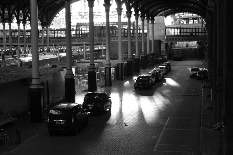 Drosjer i kø på taxiholdeplassen under taket på Liverpool Street stasjon, i svart-hvitt