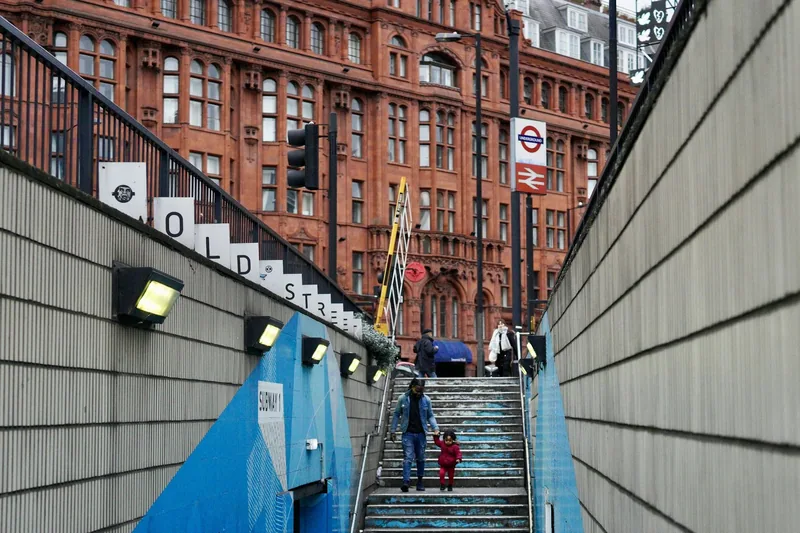 Voksen og lite barn går hånd i hånd ned trappen til Old Street stasjon