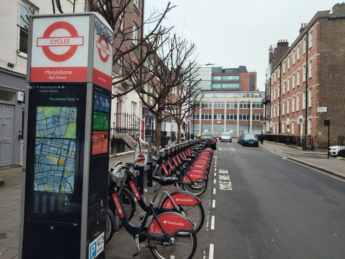 Røde Santander Cycles i dokkingstasjonen i Bell Street i Marylebone, med betalingsstander og kart