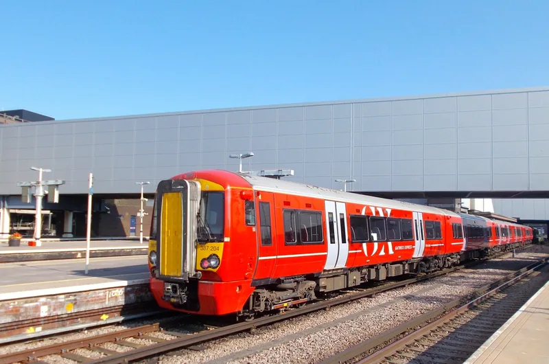 Rødt Gatwick Express-tog ved perrongen på Gatwick Airport stasjon en solfylt dag
