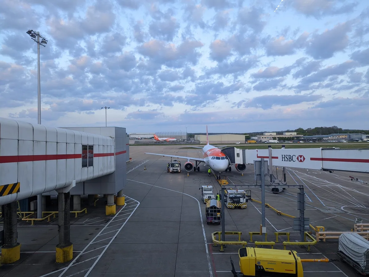 EasyJet-fly parkert ved en gate på Gatwick North Terminal under en himmel full av småskyer