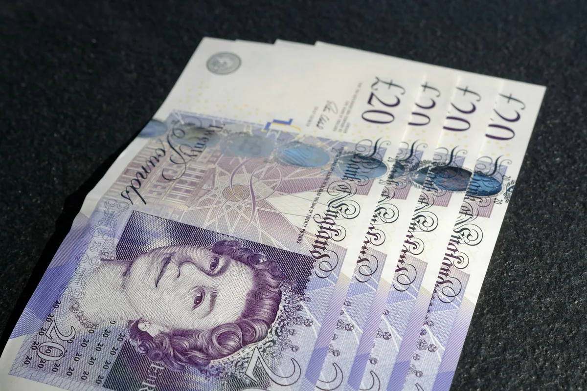 Fire 20-pundsedler fra Bank of England lagt i vifte på et mørkt underlag