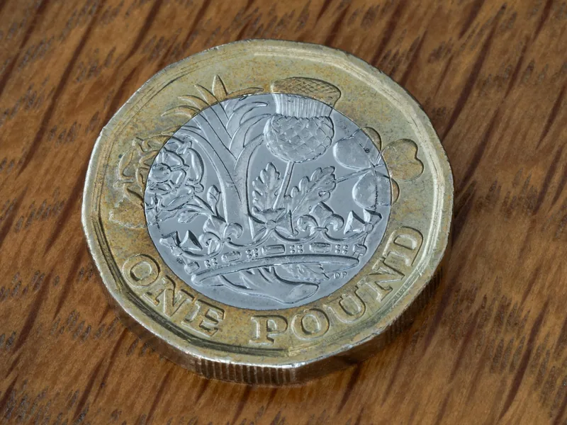 Nærbilde av en tolvkantet britisk pundmynt på et trebord